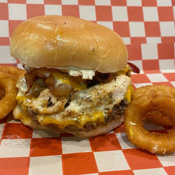 A juicy Wilson's Secret Sauce burger with melted cheese, fried egg, caramelized onions, and onion rings.